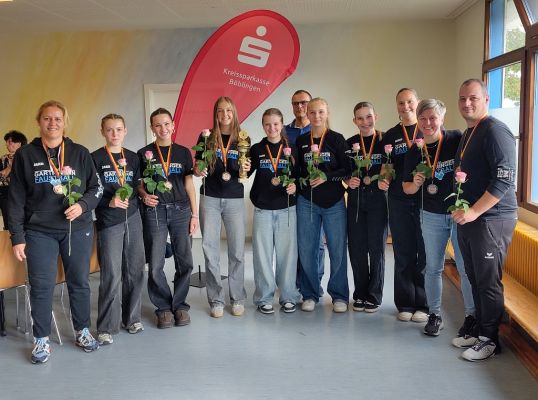 Gruppenfoto des Teams mit TrainerInnen und BetreuerInnen, alle mit Rosen in der Hand