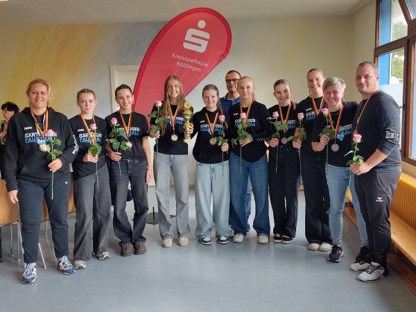 Gruppenfoto des Teams mit TrainerInnen und BetreuerInnen, alle mit Rosen in der Hand