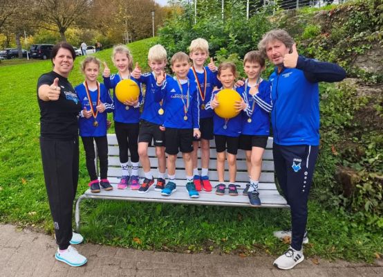 Gruppenbild beider U8 Teams mit Trainerin & Betreuer auf eine Bank vor der Sporthalle